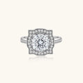 Sterling silver ring with round moissanite center stone in ornate scalloped halo setting on white background.