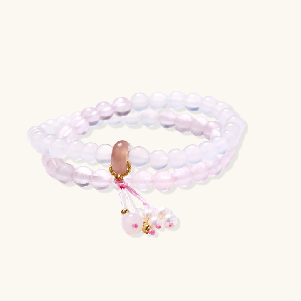 Double-wrap lavender beaded bracelet with rose quartz, pearls, gold vermeil charm and pink tassel on white background.