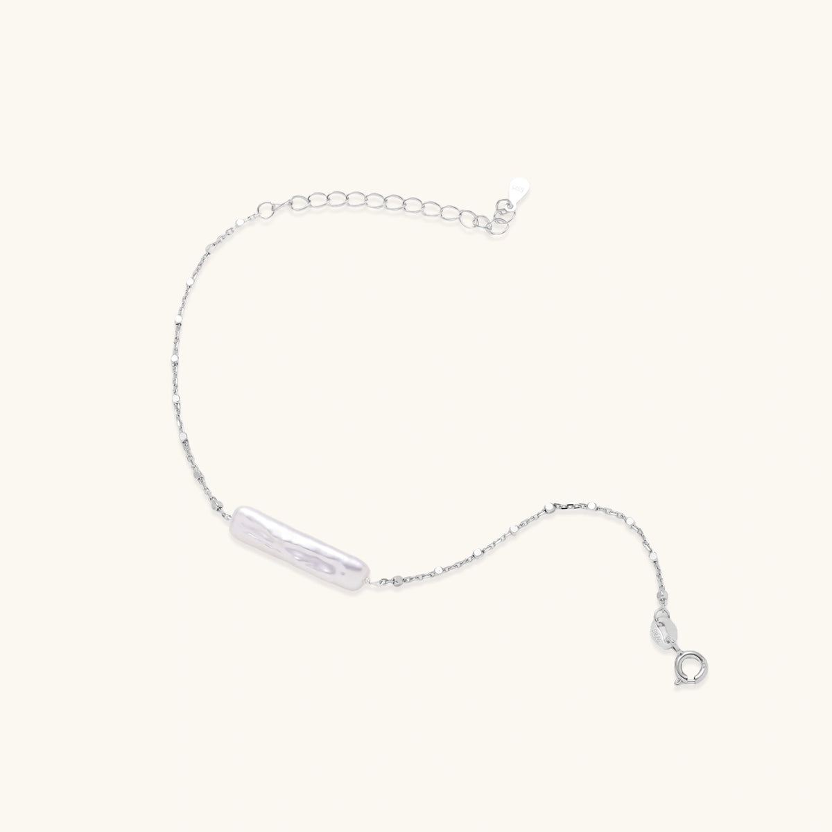 Minimalist bracelet with iridescent baroque pearl on rhodium-plated sterling silver chain against cream background