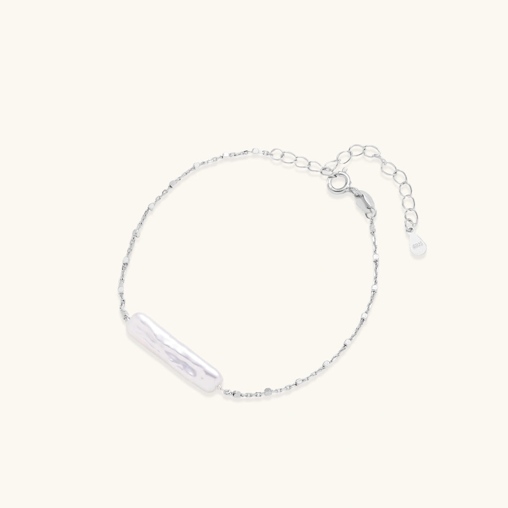 Minimalist bracelet with iridescent baroque pearl on rhodium-plated sterling silver chain against cream background