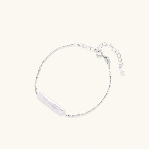 Minimalist bracelet with iridescent baroque pearl on rhodium-plated sterling silver chain against cream background