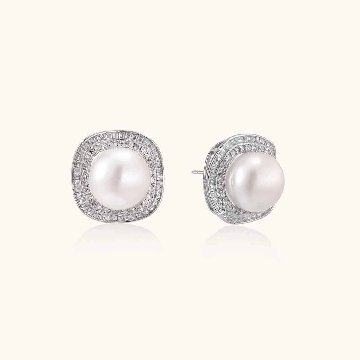 Rhodium-plated sterling silver stud earrings with round freshwater pearls surrounded by geometric crystal halos on cream background.