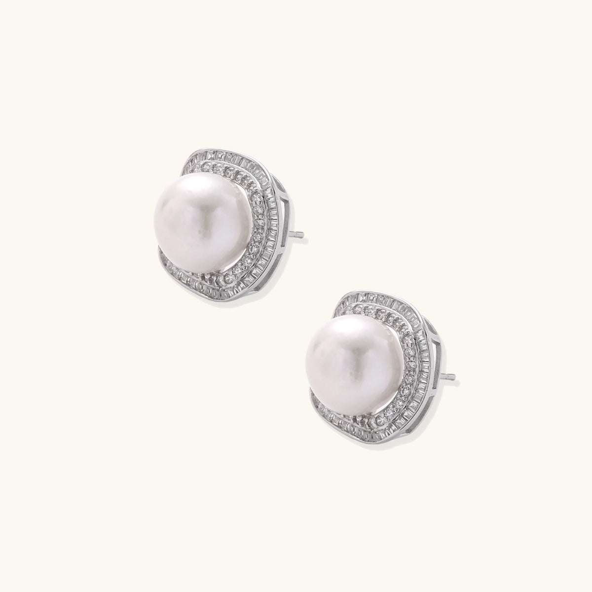 Rhodium-plated sterling silver stud earrings with round freshwater pearls surrounded by geometric crystal halos on cream background.
