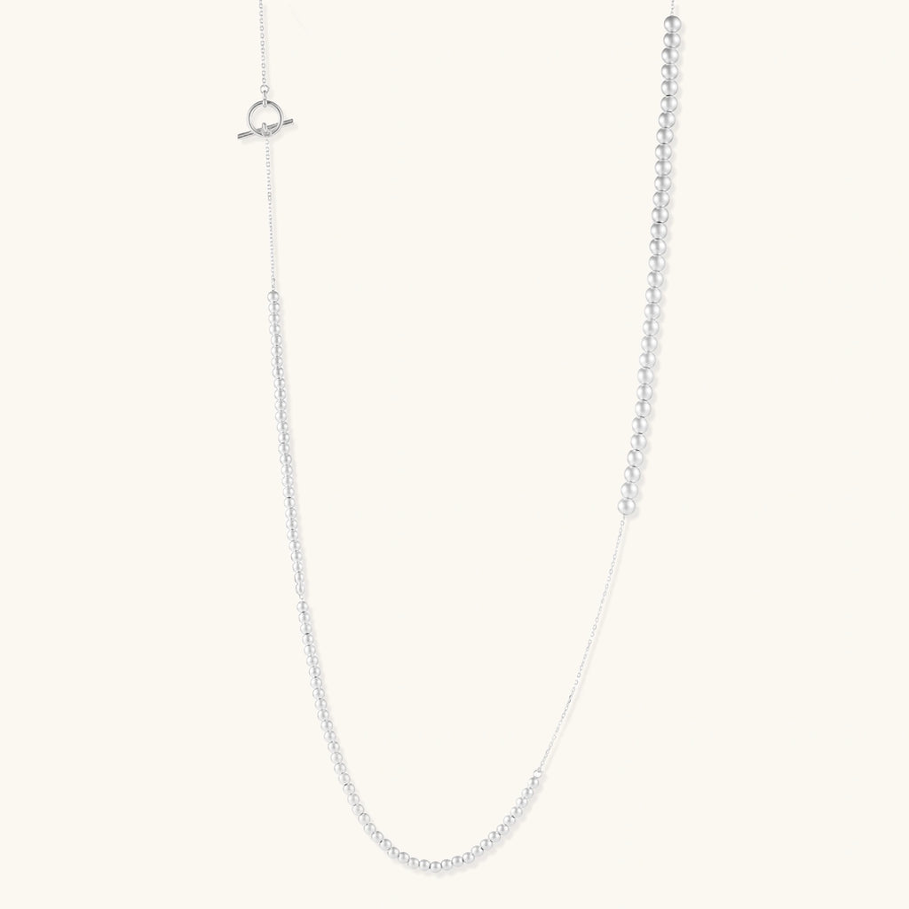 Long sterling silver beaded necklace with graduated sphere design, toggle clasp, and delicate chain extension on white background