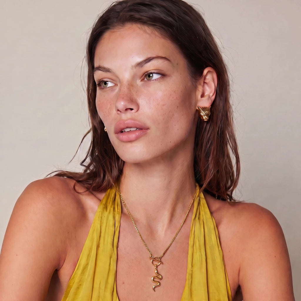 Simply Miss Meliss Serpent Power necklace in 14K gold plated stainless steel worn by a woman in a yellow top