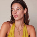 Simply Miss Meliss Serpent Power necklace in 14K gold plated stainless steel worn by a woman in a yellow top